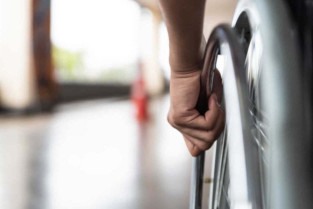 Injured worker in wheel chair wheels down a hall
