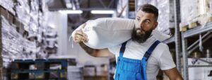 Bearded worker carries heavy load in warehouse