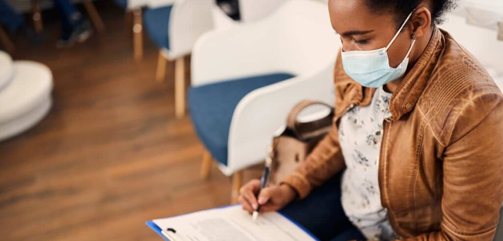 African American woman fills out insurance paperwork at a doctor's office