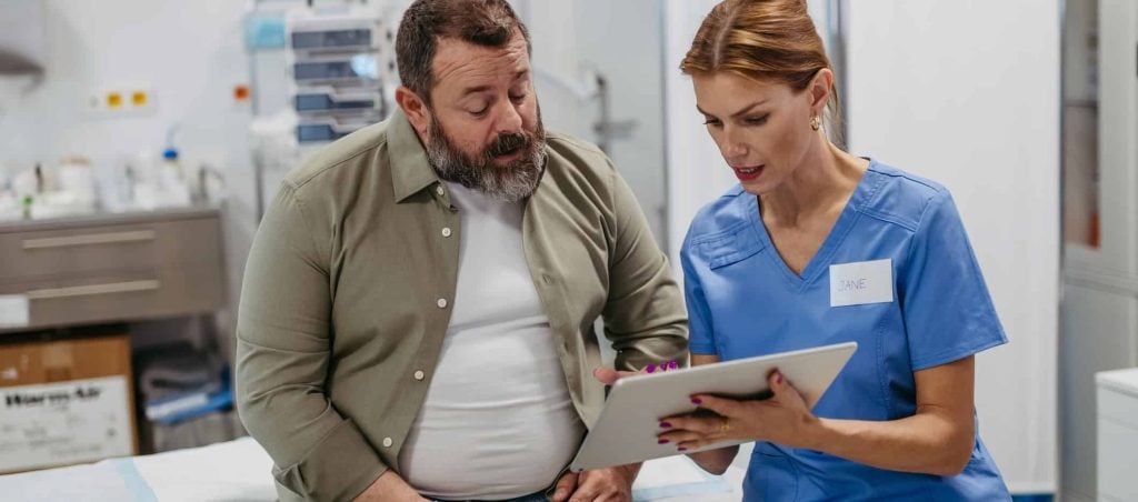 Nurse discusses treatment plan on tablet with injured Tampa worker in hospital room